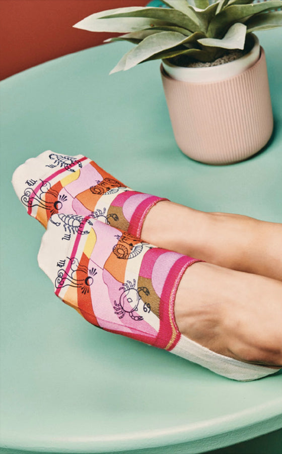 Colorful socks with cartoon designs on a light green surface, with a plant in the background.
Sælar sokkar Xpooos - hringekja - bestu sokkarnir - sætir sokkar