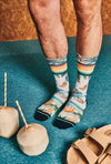 Person wearing colorful patterned socks on a blue surface with coconuts and a sandal.
Sælar sokkar Xpooos - bestu sokkarnir - sætir sokkar